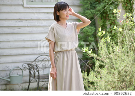 A young woman standing in front of a flower bed in the garden 90892682