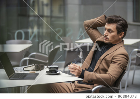 a man in a suit smokes at the table a man in a suit smokes at the table 90894378