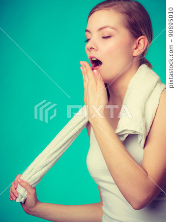 Bored sleepy woman yawning while holding towel 90895010