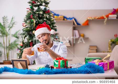Young man celebrating Christmas at home alone Young man celebrating Christmas at home alone 90895468