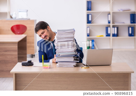 Young male employee and too much work in the office Young male employee and too much work in the office 90896815