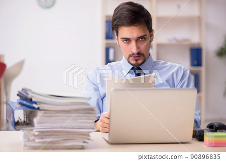 Young male employee and too much work in the office Young male employee and too much work in the office 90896835