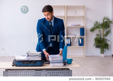 Young male employee preparing for business trip at workplace Young male employee preparing for business trip at workplace 90897040