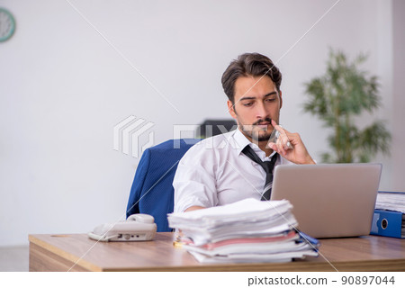 Young male employee and too much work in the office Young male employee and too much work in the office 90897044