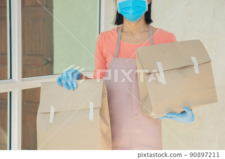 postman, delivery man wearing mask carry small box deliver to customer in front of door at home. woman wearing mask prevent covid 19, coronavirus infection outbreak. home delivery shopping concept. postman, delivery man wearing mask carry small box deliver to customer in front of door at home. woman wearing mask prevent covid 19, coronavirus infection outbreak. home delivery shopping concept. 90897211