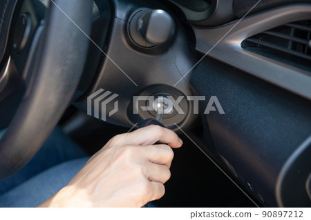 Closeup inside vehicle of hand holding key in ignition, start engine key, woman driver starting the car engine, the concept of buying a used car or a rental car. Closeup inside vehicle of hand holding key in ignition, start engine key, woman driver starting the car engine, the concept of buying a used car or a rental car. 90897212