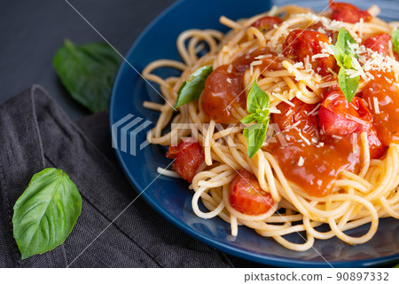 Tasty appetizing classic italian spaghetti pasta with tomato sauce, cheese parmesan and basil on plate and ingredients for cooking pasta on dark table. Tasty appetizing classic italian spaghetti pasta with tomato sauce, cheese parmesan and basil on plate and ingredients for cooking pasta on dark table. 90897332