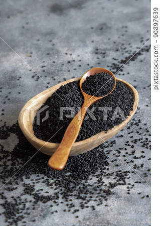 Indian spice Black cumin (nigella sativa or kalonji) seeds in bowl with spoon on wooden table close up 90897639