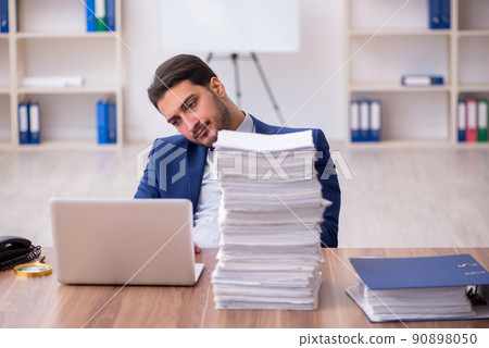 Young male employee unhappy with excessive work in the office Young male employee unhappy with excessive work in the office 90898050