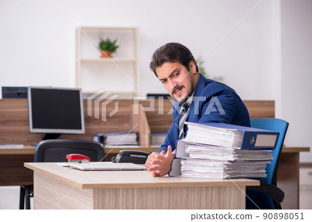Young male employee and too much work in the office Young male employee and too much work in the office 90898051