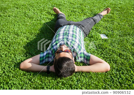 young man lie down on lawn and enjoying summertime. young man lie down on lawn and enjoying summertime. 90906532