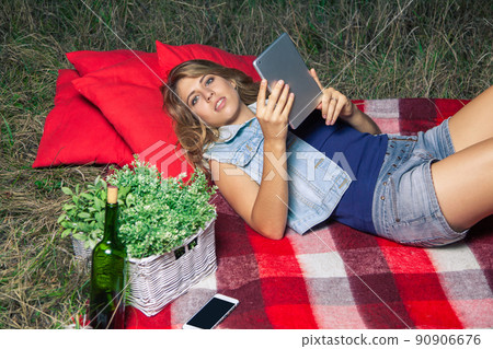Portrait of woman lie down and holding tablet on summertime outdoor Portrait of woman lie down and holding tablet on summertime outdoor 90906676