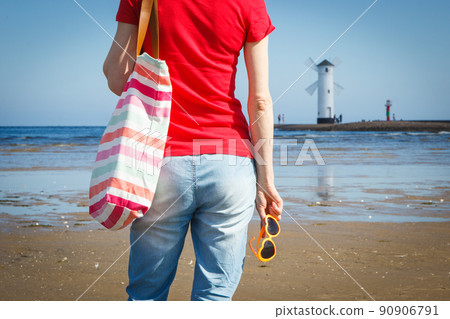 Woman with sunglasses and bag on west breakwater in Swinoujscie by navigational mark Windmill Woman with sunglasses and bag on west breakwater in Swinoujscie by navigational mark Windmill 90906791