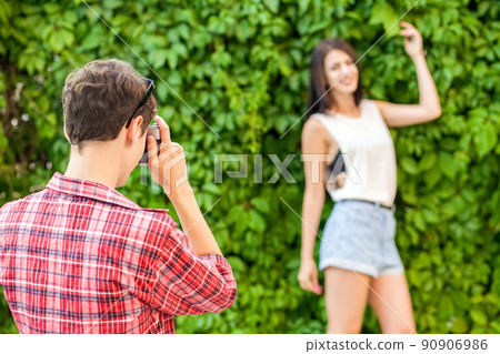 Photographer shooting beautiful brunette model near green wall. . Photographer shooting beautiful brunette model near green wall. . 90906986