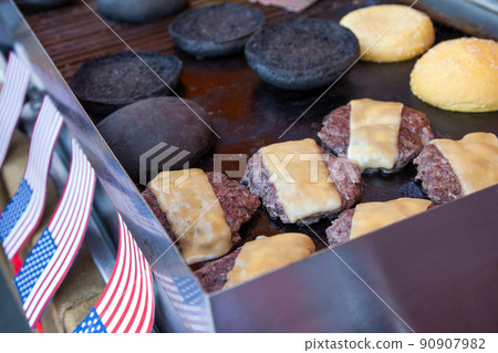 portions of beef meat with cheese and black buns grilling on stove, preparation of burgers concept portions of beef meat with cheese and black buns grilling on stove, preparation of burgers concept 90907982