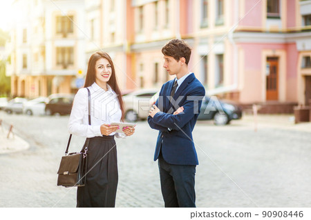 Beautiful young business woman and handsome businessman in formal suits are using a digital tablet in city background. Beautiful young business woman and handsome businessman in formal suits are using a digital tablet in city background. 90908446