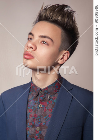 Handsome young fashion model with highlighted undercut haircut posing in blue suit in studio looking with passion on top. Handsome young fashion model with highlighted undercut haircut posing in blue suit in studio looking with passion on top. 90908986