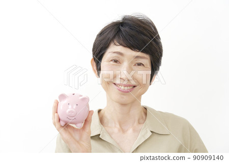 A middle-aged woman holding a piggy bank and laughing at the camera on a white background A middle-aged woman holding a piggy bank and laughing at the camera on a white background 90909140