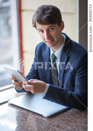 young man in business suit sitting in office and working young man in business suit sitting in office and working 90909723