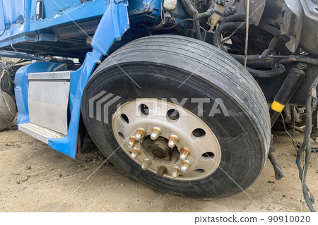Closeup of abandoned truck in a junkyard, a blue lorry with a destroyed wheel and other parts after an accident on the road, big broken automobile on a junk yard. 90910020