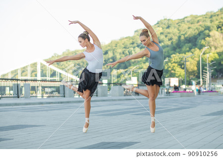 Two young beautiful twin sister dancing ballet in the city with ballet costume. urban sync dance. industrial street dancing. with special effect. synced posing. pointe ballet shoes and dress. Two young beautiful twin sister dancing ballet in the city with ballet costume. urban sync dance. industrial street dancing. with special effect. synced posing. pointe ballet shoes and dress. 90910256