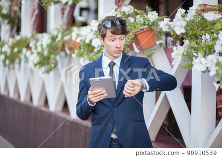 young man in business suit holding tablet on summertime day. young man in business suit holding tablet on summertime day. 90910539