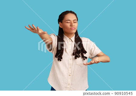 Portrait of blind woman with outstretched hands walking alone with closed eyes in darkness, feeling disoriented confused, lost road, wearing white shirt. Indoor studio shot isolated on blue background 90910545