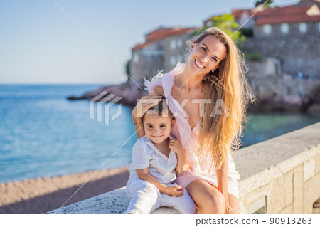 Mother and son tourists on background of beautiful view St. Stephen island, Sveti Stefan on the Budva Riviera, Budva, Montenegro. Travel to Montenegro concept Mother and son tourists on background of beautiful view St. Stephen island, Sveti Stefan on the Budva Riviera, Budva, Montenegro. Travel to Montenegro concept 90913263