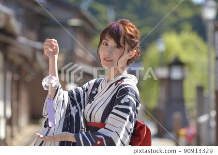 A young woman wearing a yukata smiling with a wind chime and the streets of Little Edo Sawara A young woman wearing a yukata smiling with a wind chime and the streets of Little Edo Sawara 90913329