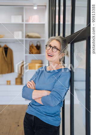 Elderly female keeping arms folded on her chest, looking at camera with confident smile 90913388