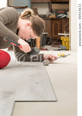 Quartz vinyl flooring and installation, a woman knocks a rubber hammer on the floor locks. 90914613