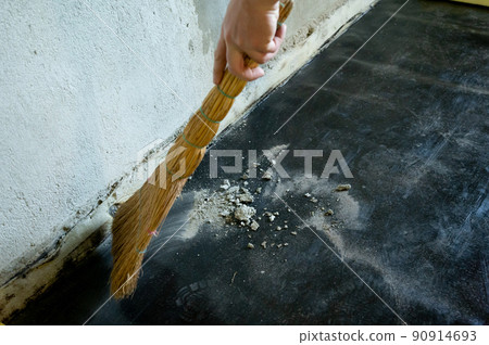 Worker sweeps construction debris with a broom. Worker sweeps construction debris with a broom. 90914693