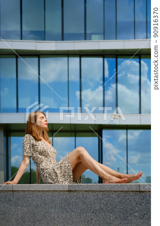 Barefoot woman in dress and sandals sitting in profile 90916370