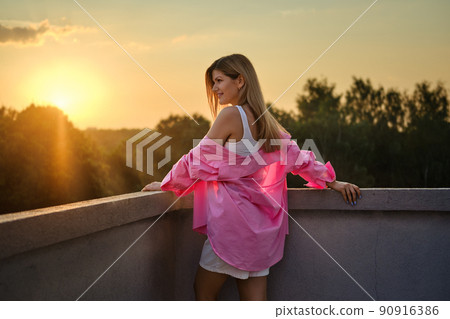 Happy woman leaning to balcony and watching the sunset 90916386