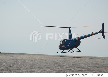 Blue helicopter flying in grey cloudy skies Blue helicopter flying in grey cloudy skies 90918349