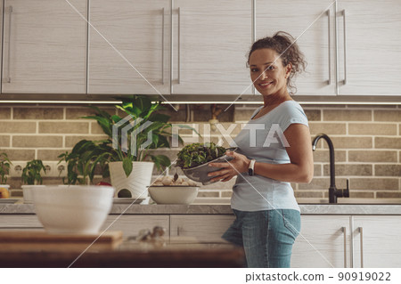 Smiling woman using green salad and vegetables while cooking breakfast Smiling woman using green salad and vegetables while cooking breakfast 90919022