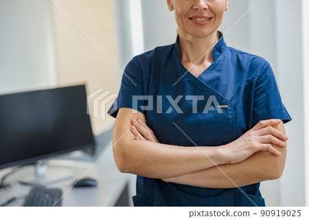 Close up of doctor in uniform standing with crossing hands in clinic 90919025