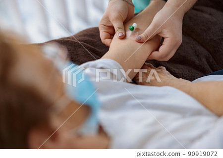 Nurse putting a drip in the arm of her patient in modern medical clinic 90919072