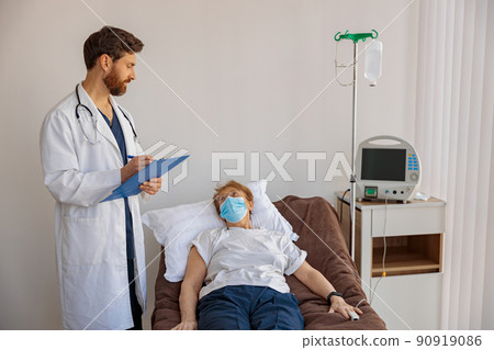 Doctor writing down patient symptoms in hospital ward during Covid-19 epidemic Doctor writing down patient symptoms in hospital ward during Covid-19 epidemic 90919086