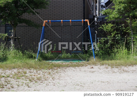 Scenery of a park in a residential area with green vegetation and swings Scenery of a park in a residential area with green vegetation and swings 90919127