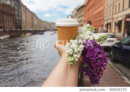 paper cup of natural coffee in woman's palm with flower on background of Moika river in St. Petersburg paper cup of natural coffee in woman's palm with flower on background of Moika river in St. Petersburg 90920155