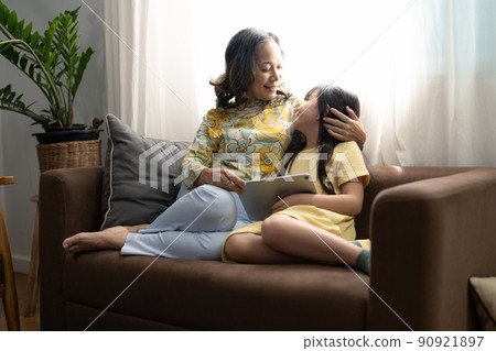 Asian portrait, Grandma and granddaughter doing recreational activities playing tablet computers on the sofa 90921897