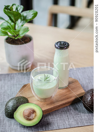 Avocado smoothie energy drink in the glass and bottle on the wood plate Avocado smoothie energy drink in the glass and bottle on the wood plate 90928201