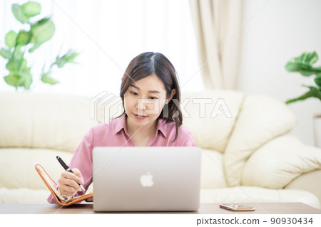 A woman in her thirties working from home in the living room 90930434