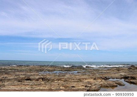 The waves hitting the rocks create a white spray 90930950