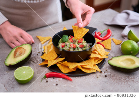 Guacamole dip with tortilla chips or nachos on black serving board Guacamole dip with tortilla chips or nachos on black serving board 90931320