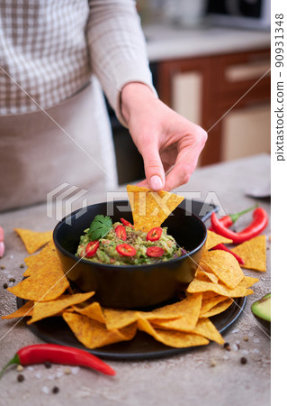Guacamole dip with tortilla chips or nachos on black serving board Guacamole dip with tortilla chips or nachos on black serving board 90931348