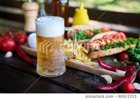 BBQ hot dog served with vegetables and French fries and sauces on wooden serving board 90931355