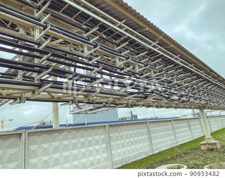 construction of a new complex at the plant. metal structures for the erection of a new building behind a white metal fence. the passage for people is closed construction of a new complex at the plant. metal structures for the erection of a new building behind a white metal fence. the passage for people is closed 90933482