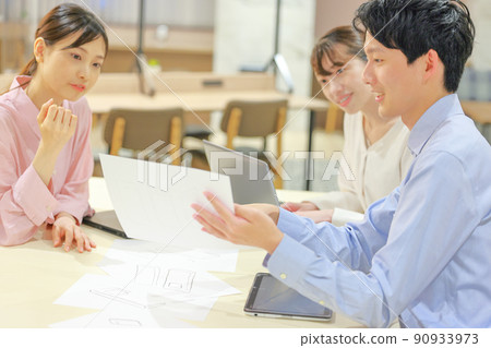 A designer and a business person who have a meeting while looking at a design drawing 1 90933973